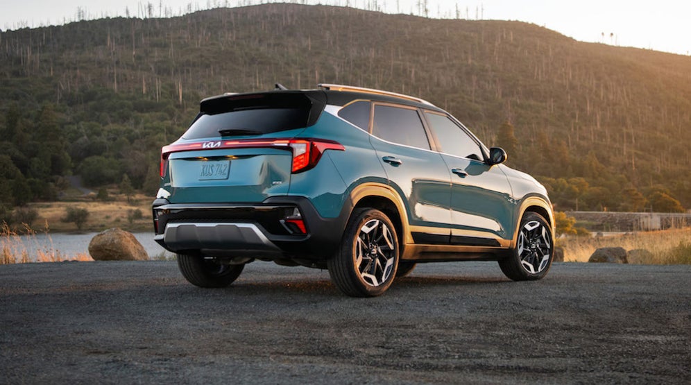 A blue 2026 Kia Seltos parked by a body of water, with a hill in the background