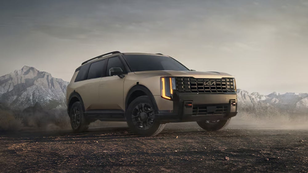 A bronze Kia Telluride SUV driving over dusty terrain