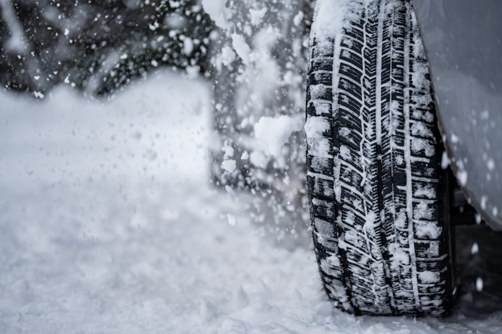 A closeup of a vehicle’s tire in the snow