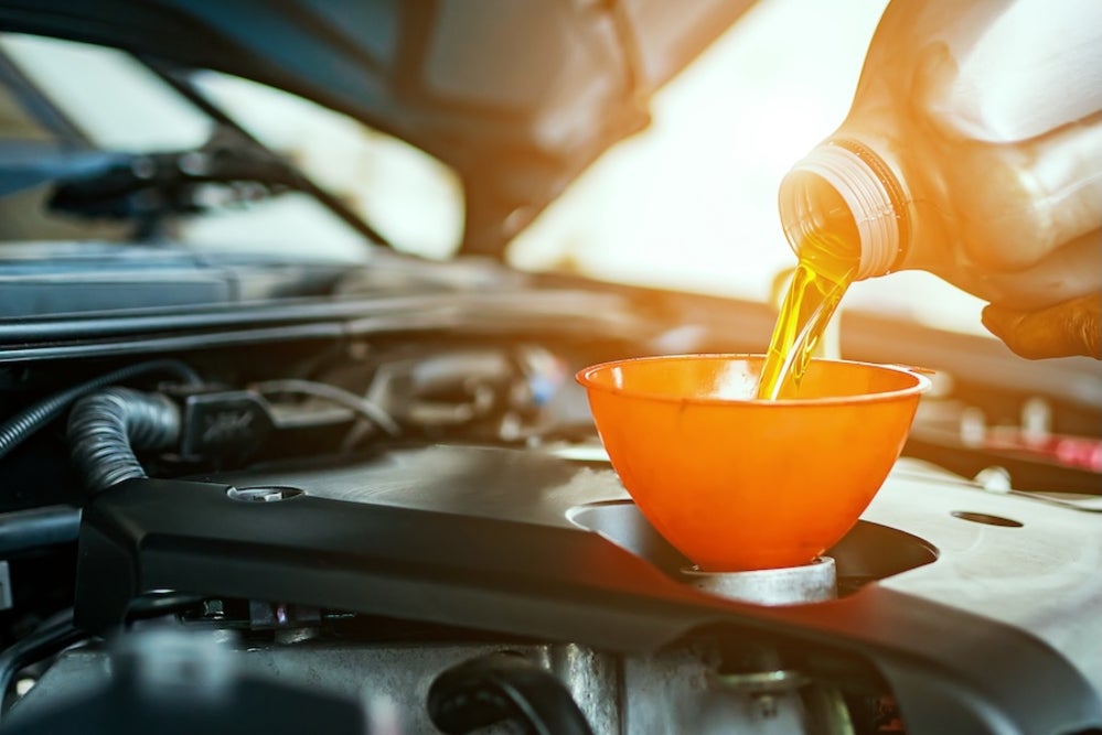 Engine oil being poured into a car’s engine via a funnel
