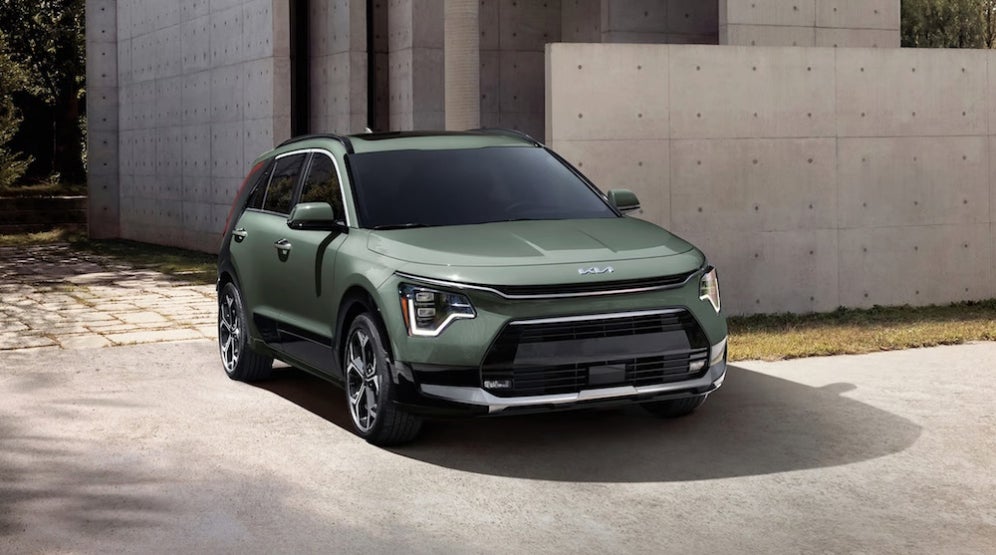 A green 2026 Kia Niro SUV parked beside a concrete wall